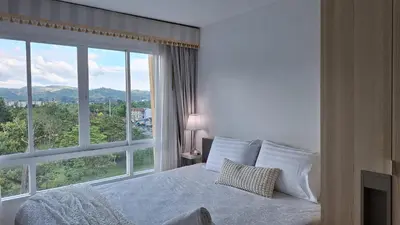 a bedroom with a bed and a large window at Plus condo 2 kathu by Tida in Kathu