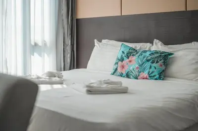 a white bed with a blue pillow and towels on it at C153 The Aristo Luxury Beach Resort Phuket in Thalang