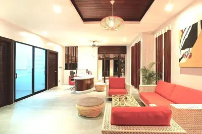 a living room with a red couch and a table at Emerald Terrace Serenity 11 - 5th Floor Garden View by PSR in Patong Beach