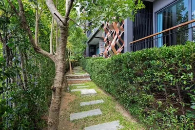 a tree with a stepping stone path next to a building at Emerald Terrace Serenity 11 - 5th Floor Garden View by PSR in Patong Beach