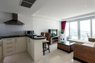 a kitchen with white cabinets and a living room at ELEGANT Kata sea View Apartmens in Kata Beach