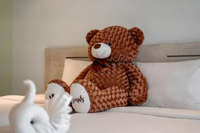 a teddy bear sitting on top of a bed at ELEGANT Kata sea View Apartmens in Kata Beach