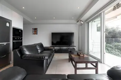 a living room with a black leather couch and a television at ELEGANT Kata sea View Apartmens in Kata Beach