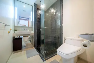 a bathroom with a toilet and a glass shower at Luxury Flat 2BR at CHAVA 5-Star Resort in Surin Beach