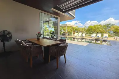 a dining room with a table and chairs and a pool at Villa Lion Phuket in Phuket
