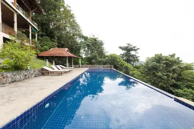 a swimming pool with two chairs and a gazebo at Villa Moon Talay Panorama View in Patong Beach