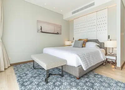 a bedroom with a large white bed and a blue rug at Infinite Ocean Retreats at Angsana Oceanview in Laguna Phuket