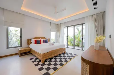 a bedroom with a bed and a table and windows at Spacious 4BR Private 15m Pool Villa Anchan V10 in Gated Residence in Bang Tao Beach