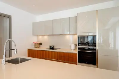 a kitchen with white cabinets and a black appliance at Spacious 4BR Private 15m Pool Villa Anchan V10 in Gated Residence in Bang Tao Beach