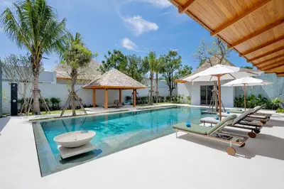 a swimming pool with lounge chairs and umbrellas at Spacious 4BR Private 15m Pool Villa Anchan V10 in Gated Residence in Bang Tao Beach