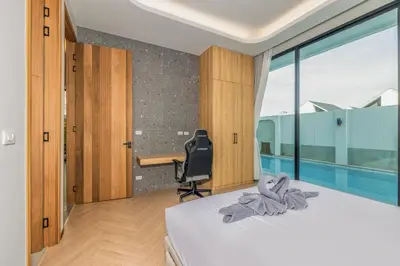 a bedroom with a bed and a desk and a window at Bangtao Pool Villa with Home Cinema - PrymaVista in Phuket