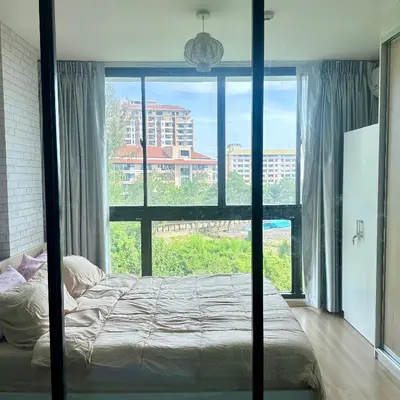 a bedroom with a bed and a large window at Connext Condominium By January in Ban Tha Khreng