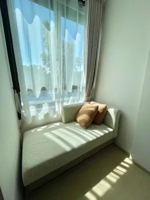 a couch sitting in front of a window with two pillows at 1 bedroom pool view in Bangtao in Thalang