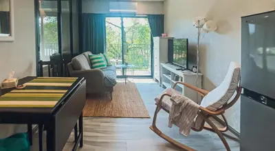 a living room with a chair and a table and a tv at Apartments pool view in Title Residence Naiyang in Nai Yang Beach