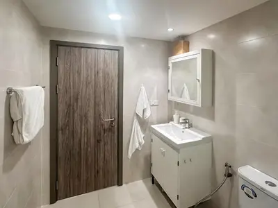 a bathroom with a sink and a wooden door at Apartments pool view in Title Residence Naiyang in Nai Yang Beach