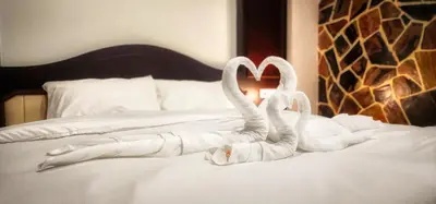 two swans made out of towels sitting on a bed at Arya Suites Patong Beach in Patong Beach