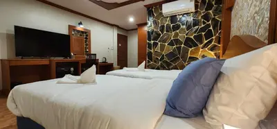 a hotel room with two beds and a flat screen tv at Arya Suites Patong Beach in Patong Beach
