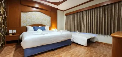 a hotel room with two beds and a window at Arya Suites Patong Beach in Patong Beach