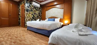 a hotel room with two beds and a wall at Arya Suites Patong Beach in Patong Beach