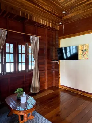 a living room with wooden walls and a table and a screen at Chaba House Koh Yao Noi in Ban Laem Sai