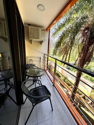 a balcony with tables and chairs and a palm tree at NBC апартаменты у пляжа in Rawai Beach