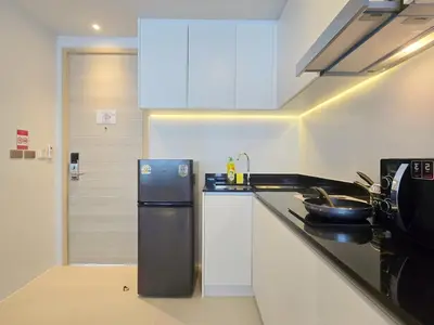 a kitchen with white cabinets and a refrigerator at Karon Utopia in Karon Beach