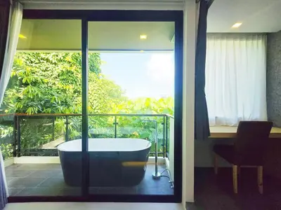 a bath tub in a room with a balcony at Karon Utopia in Karon Beach