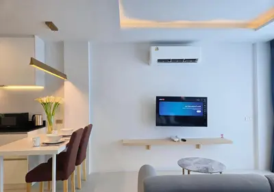 a living room with a table and a tv on a wall at Karon Utopia in Karon Beach