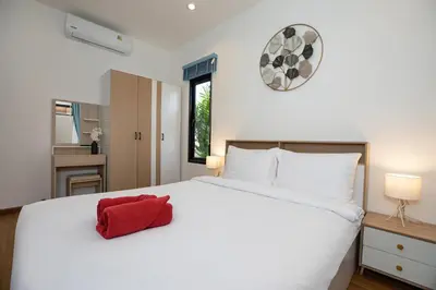 a bedroom with a white bed with a red pillow on it at Newly Built 3BR Pool Villa Goldena 12B in Kamala in Kamala Beach