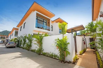 a white house with palm trees in front of it at Newly Built 3BR Pool Villa Goldena 12B in Kamala in Kamala Beach