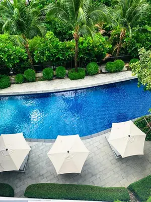 a pool with two white umbrellas next to a swimming pool at Cozy Paradise By Rawai Beach in Phuket Town