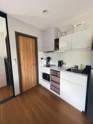 a kitchen with white cabinets and a wooden door at Cozy Paradise By Rawai Beach in Phuket Town