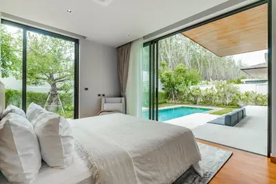 a bedroom with a large bed and a pool at Botanica Modern Loft by Villacarte in Ban Pak Lak