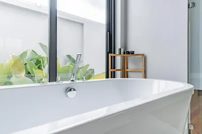 a white bath tub in a bathroom with a window at Botanica Modern Loft by Villacarte in Ban Pak Lak