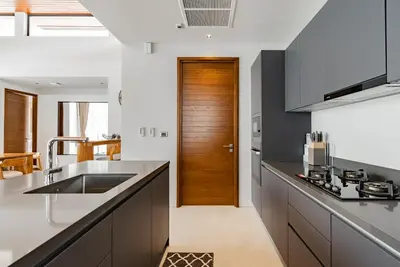a kitchen with a sink and a wooden door at Botanica Modern Loft by Villacarte in Ban Pak Lak