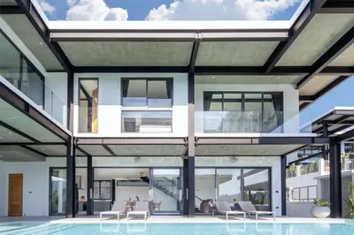 an exterior view of a house with a pool at New & Modern, Loft Style 4BR Villa Sunset Garden 3, 12m Salt Pool, just 10min drive Naiharn Beach in Rawai Beach