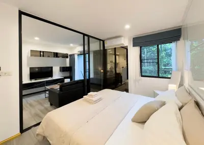a bedroom with a large white bed and a living room at The Title Residences Apartment 7 min walk to Nai Yang Beach in Nai Yang Beach