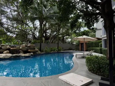 a swimming pool in a yard with an umbrella at The Title Residences Apartment 7 min walk to Nai Yang Beach in Nai Yang Beach