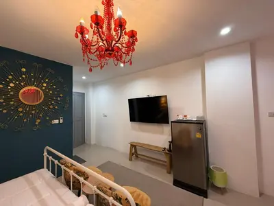 a living room with a chandelier and a tv at Five Loaves Beds Patong in Patong Beach