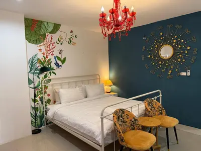 a bedroom with a bed and two chairs and a chandelier at Five Loaves Beds Patong in Patong Beach