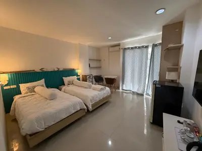 a bedroom with two beds and a green wall at Five Loaves Beds Patong in Patong Beach