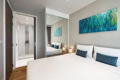 a bedroom with a large white bed and a mirror at Diamond Resort in Bang Tao Beach