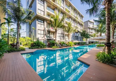 a swimming pool in front of a building with palm trees at Diamond Resort in Bang Tao Beach