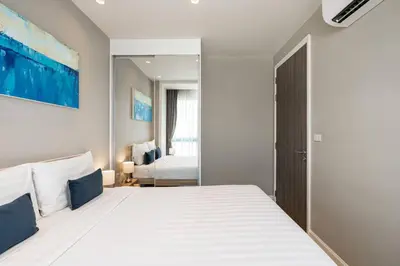a bedroom with a large white bed with a mirror at Diamond Resort in Bang Tao Beach