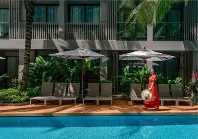a woman in a red dress standing next to a pool at Diamond Resort in Bang Tao Beach