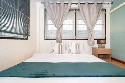 a bedroom with a large white bed with two windows at Rawai Cottage House in Rawai Beach
