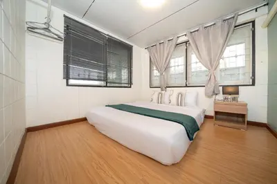 a white bedroom with a large white bed and windows at Rawai Cottage House in Rawai Beach