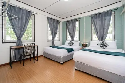 two beds in a room with two windows at Rawai Cottage House in Rawai Beach