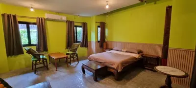 a bedroom with yellow walls and a bed and chairs at Baibon 4 Homestay Thalang Phuke in Thalang