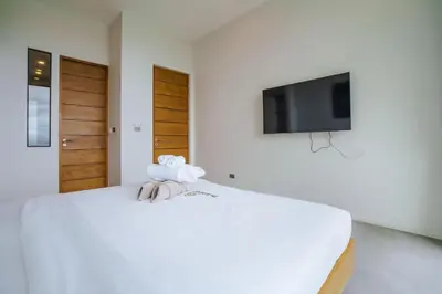 a bedroom with a bed with a tv on the wall at Lapista 6 Bedroom Luxury Vila in Phuket Town